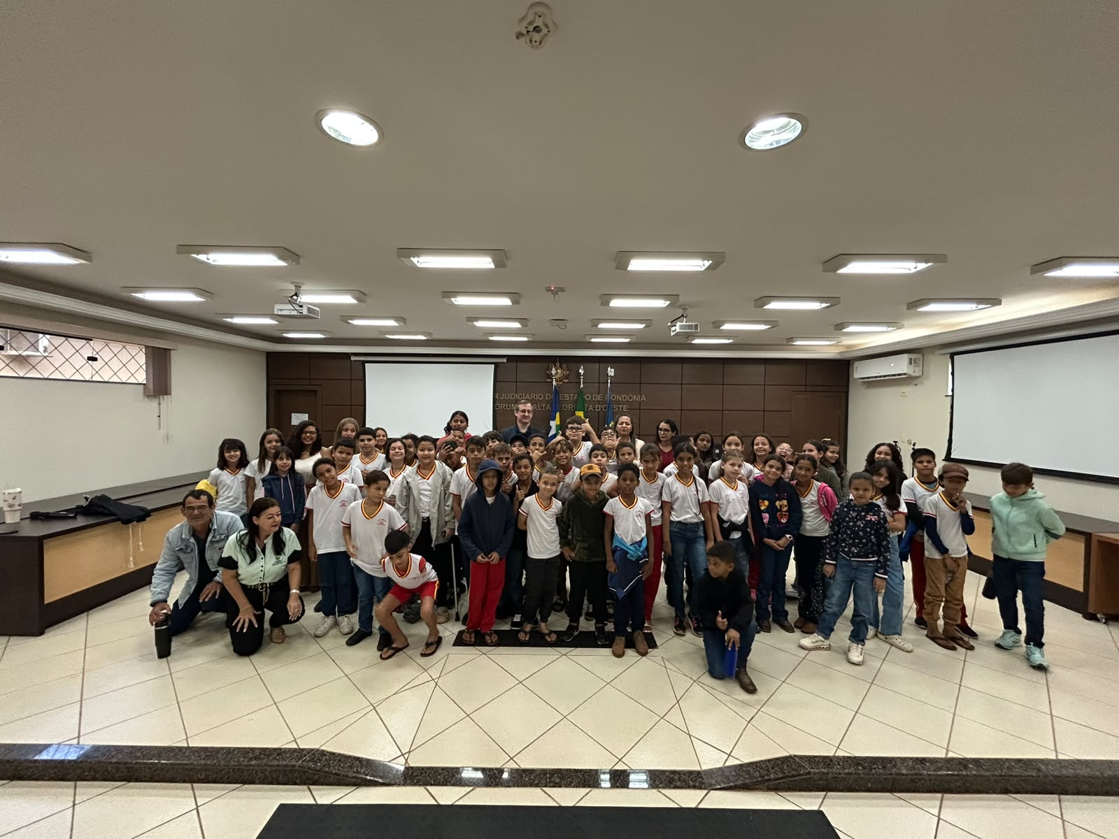 Fotografia mostra juíza Paula palestrando no auditório com crianças